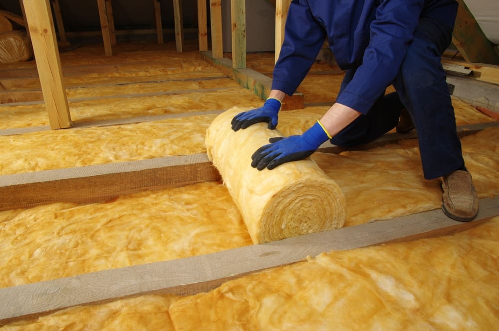 Man installing thermal insulation under a roof using mineral wool